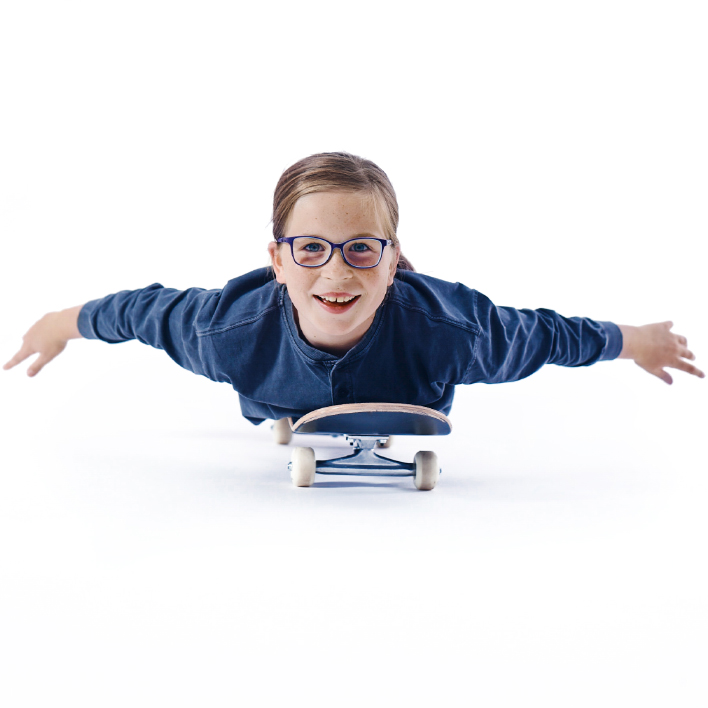 Una joven con lentes sobre su monopatín.